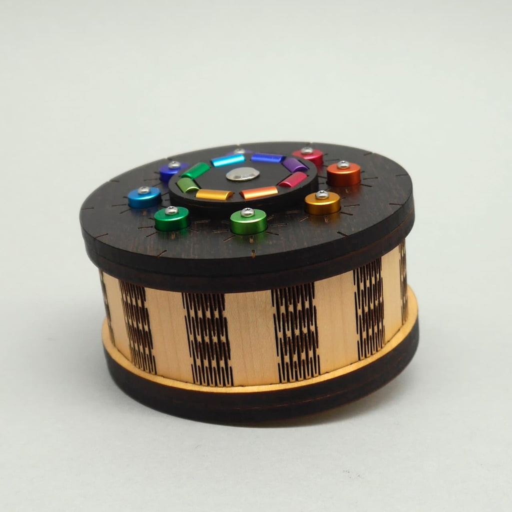 Niedrig aufgenommene Perspektive einer Trickkiste mit mehrfarbigen Bedienelementen auf dem Deckel – eine herausfordernde Geduldsspielbox aus Holz.
