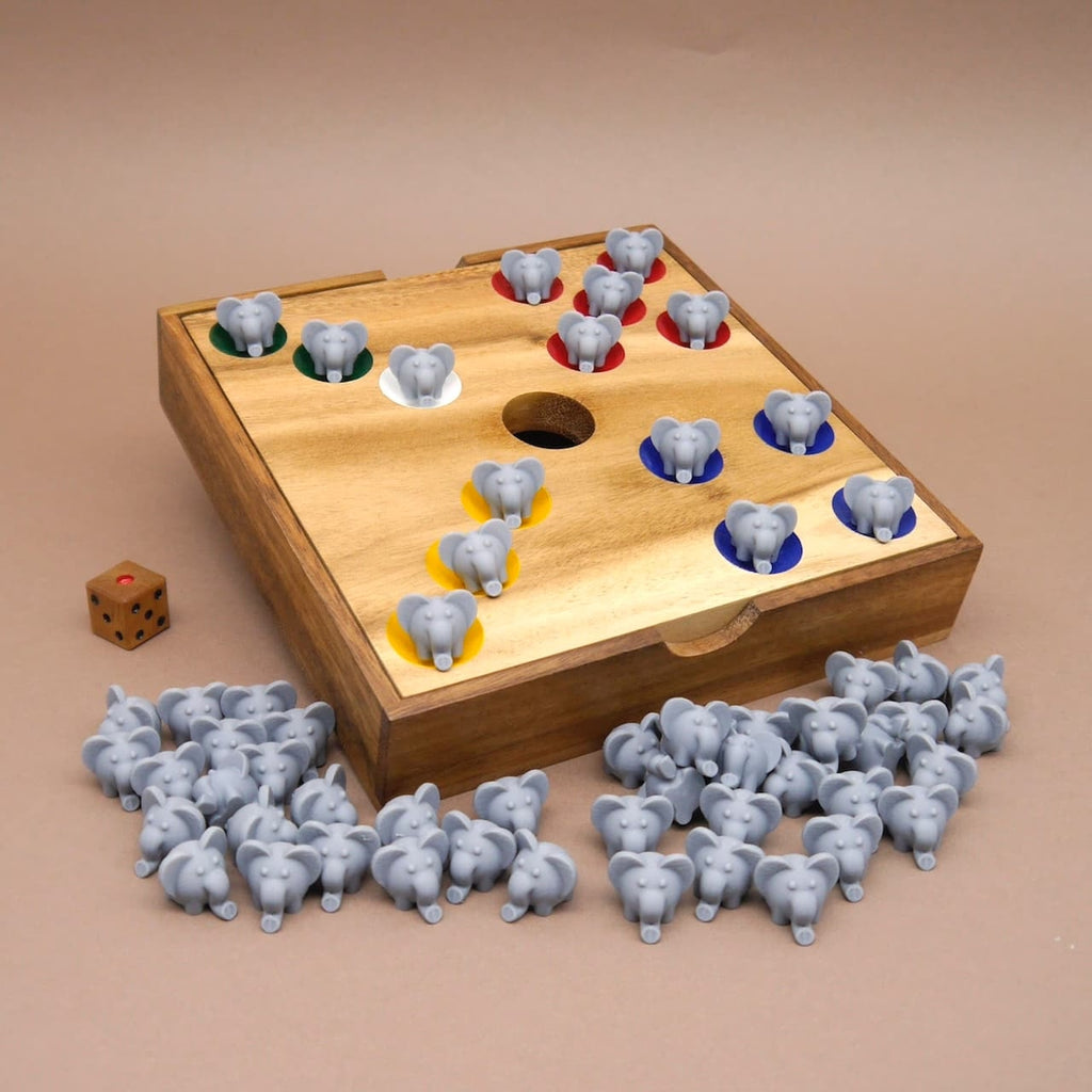 Holzbrett als Würfelspiel mit farbigen Kreisen für Elefantenfiguren, einem Loch in der Mitte, vielen grauen Elefanten und einem Holzwürfel daneben.