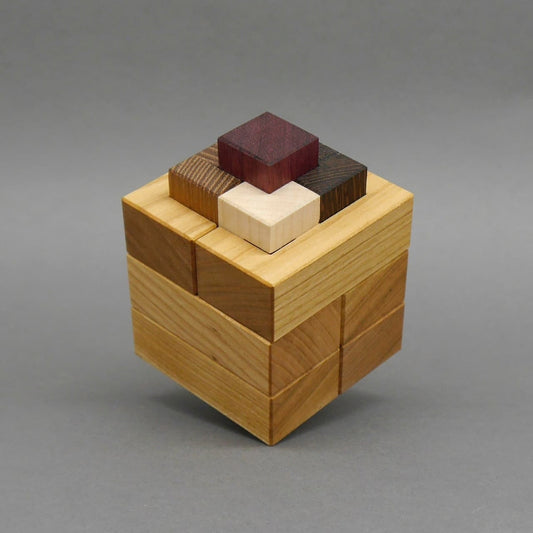 Holzpuzzle in Würfelform mit präzise ineinandergreifenden Bausteinen in mehreren Holzfarben.
