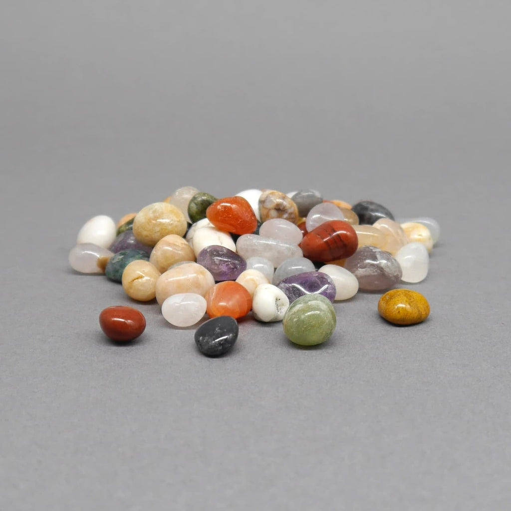 Polierte Ersatzsteine in verschiedenen Farben für Kalaha oder Mancala Bohnenspiele auf grauer Fläche.