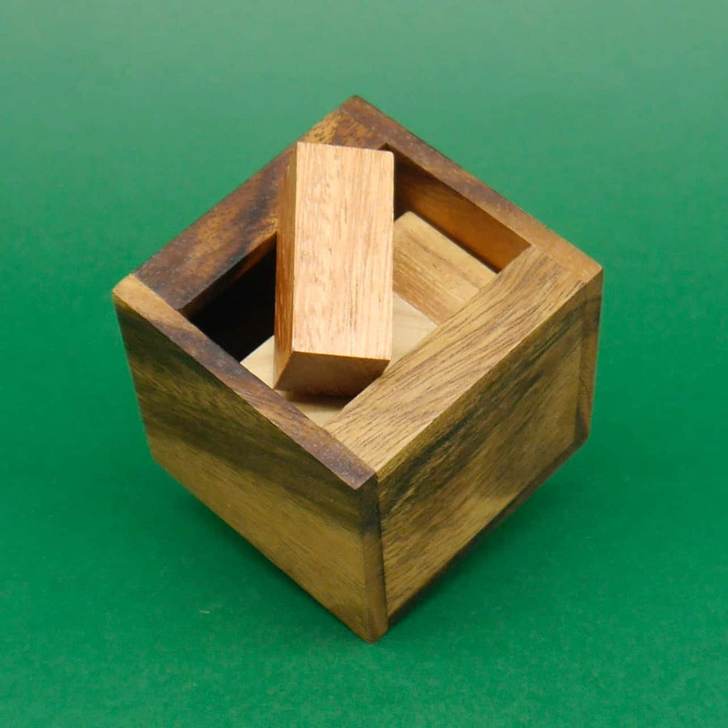 Quadratisches Holzpuzzle als Denksport-Herausforderung: Aus der offenen Box ragt ein länglicher Quader.