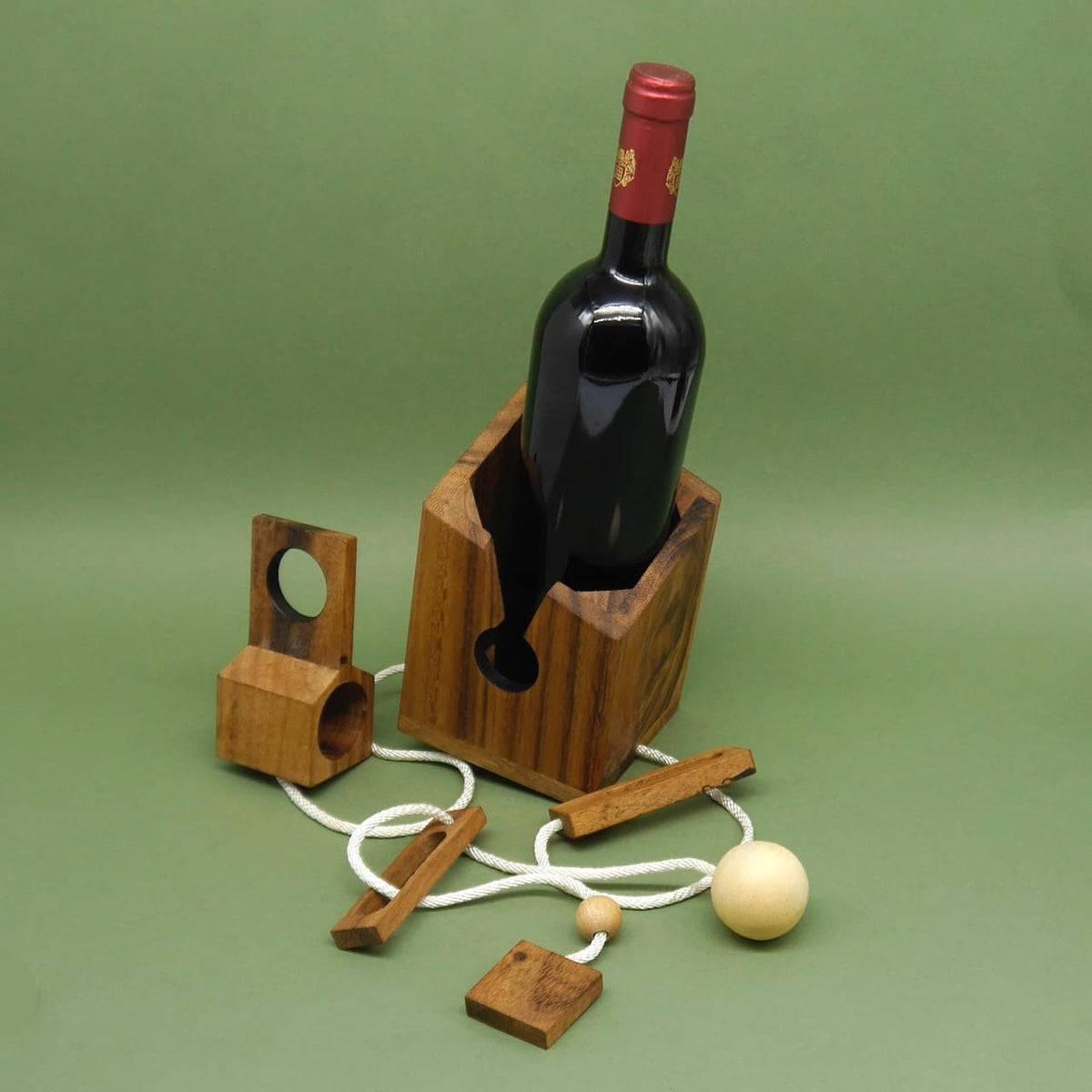 Holzpuzzle-Flaschensafe als Denkspiel: Holzbox mit eingesetzter Weinflasche, losem Seil und Holzteilen als originelle Geschenkverpackung für Spirituosen.
