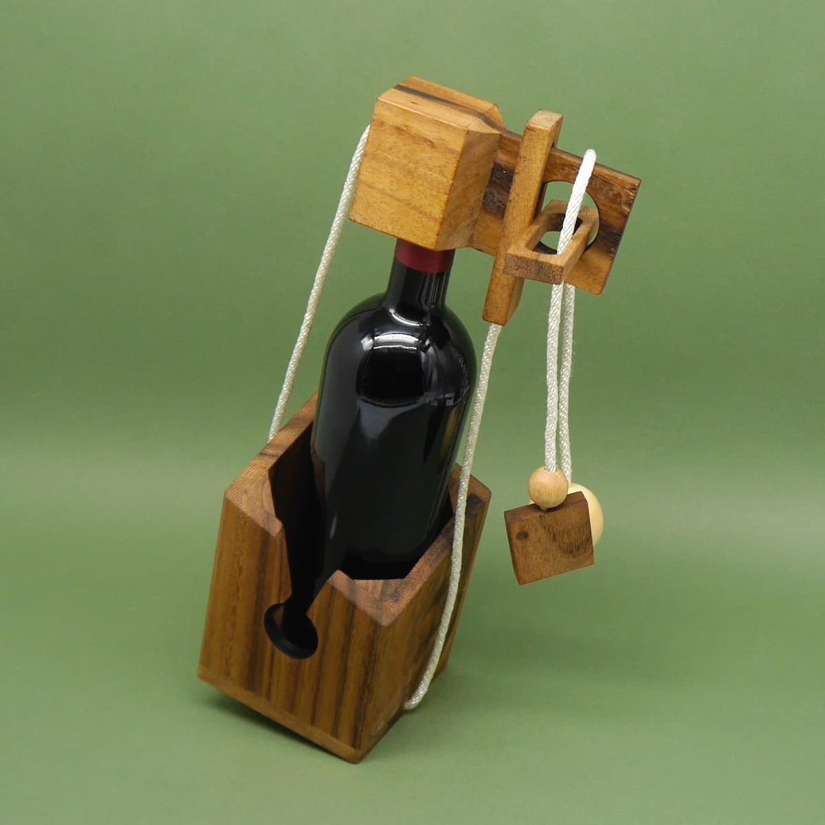 Flaschensafe beim Flaschengeschenk: Weinflasche steckt in einer Holzhalterung mit Seilpuzzle und hängenden Holzelementen, kreativ zum Verschenken.