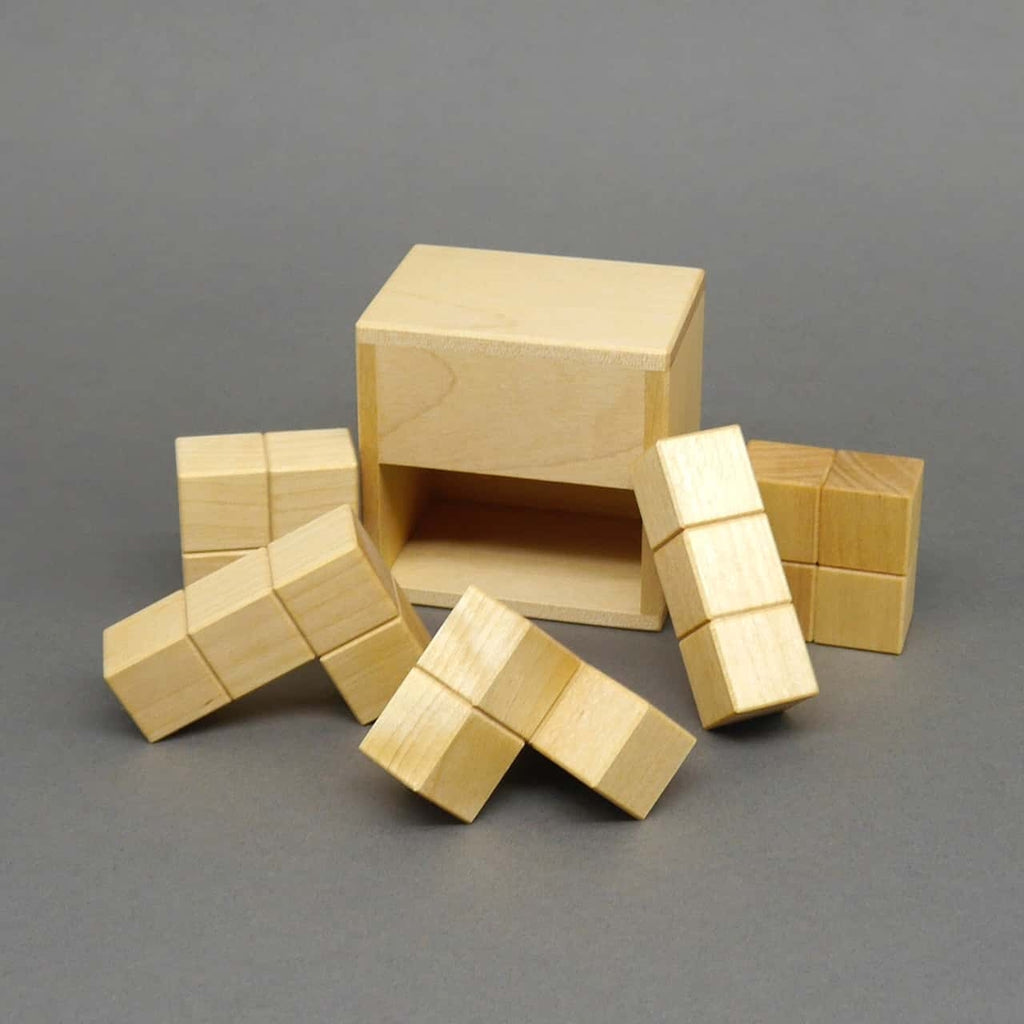 Holz-3D-Puzzle für Gehirntraining: mehrere winkelförmige Würfelteile liegen verstreut vor einer leeren, offenen Box.