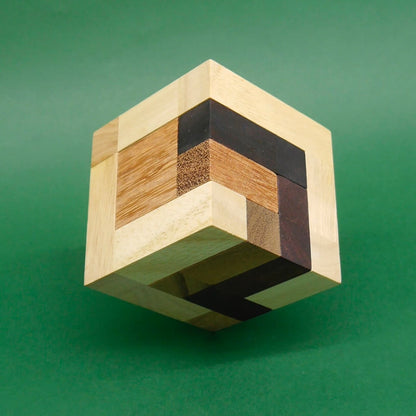 Schwebend fotografierter Holzwürfel aus hellen und dunklen Holzsegmenten – ideales Puzzle zum Knobeln.