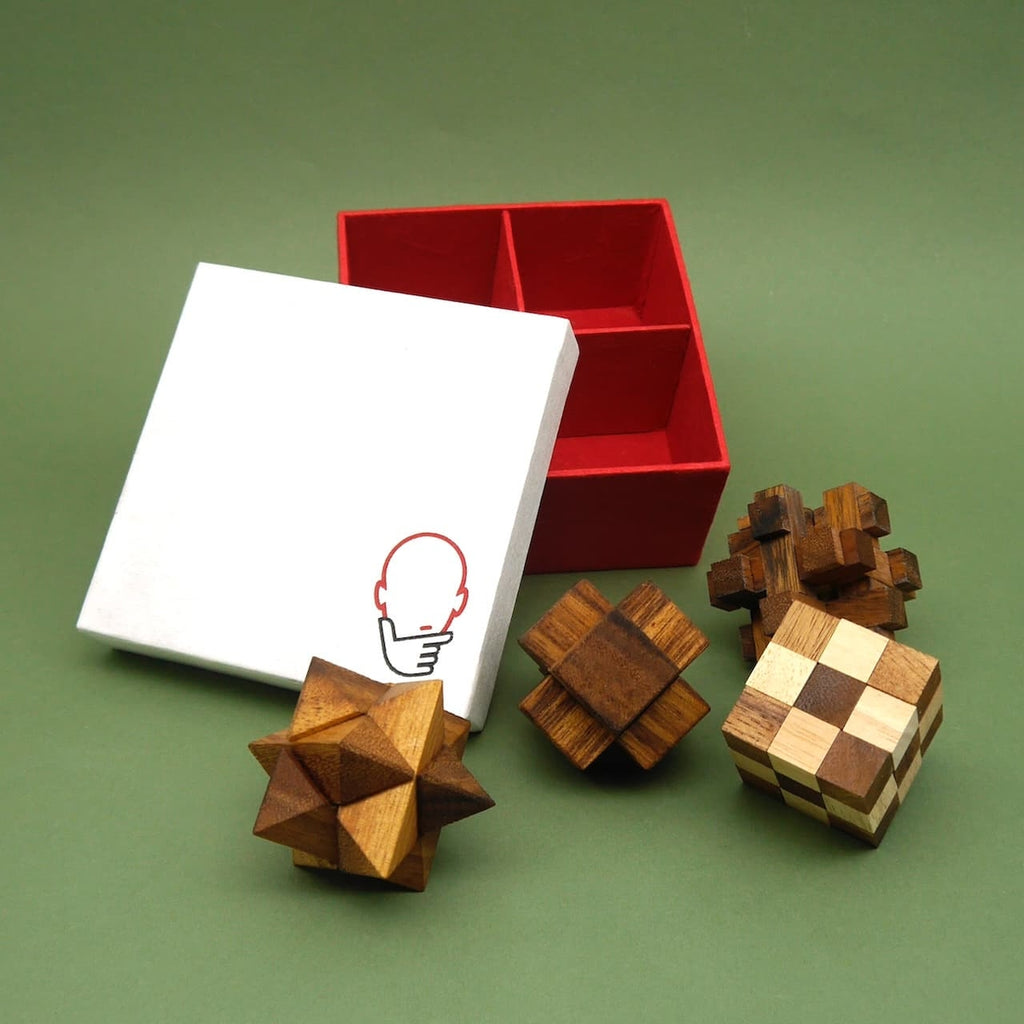 Vier verschiedene hölzerne Logikpuzzle liegen neben einer geöffneten, rot-weißen Box mit Fächern – ideal für Fans von Denkspielen.