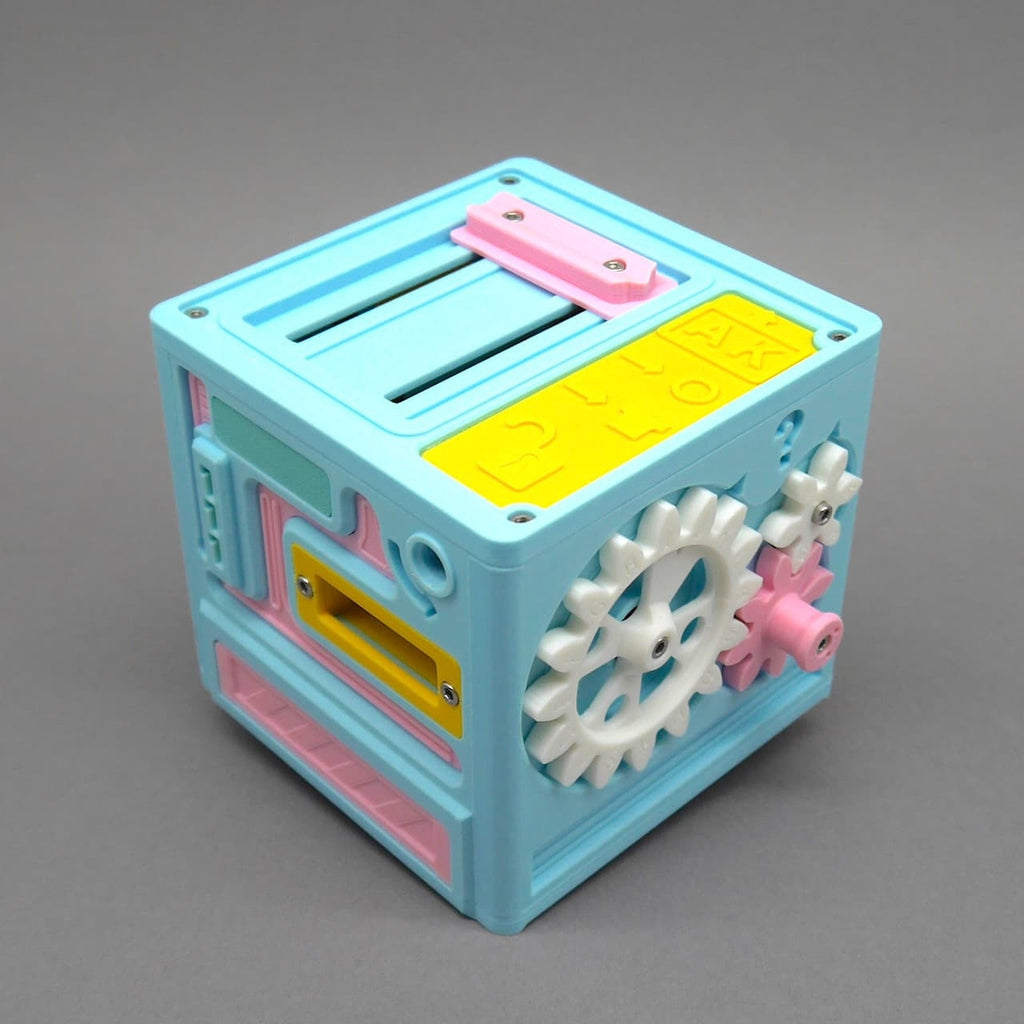 Bunte Knobelbox in Würfelform mit Zahnrädern und Schiebemechanismen, in Pastellfarben gehalten – ideal für Escape Room Fans.