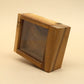Aufrecht stehende Mystery‑Box aus glattem Holz mit Sichtfenster, vor neutralem Hintergrund abgelichtet.