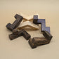 Ringförmig ausgelegte Teile eines Interlocking-Puzzle aus hellem und dunklem Holz liegen auf beigem Untergrund