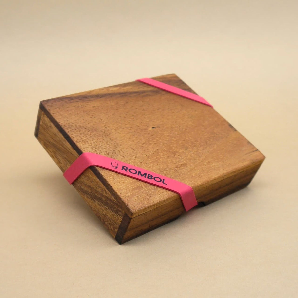 Quadratische Holzbox, als Geschenk mit pinkem ROMBOL‑Gummiband sicher verschlossen.