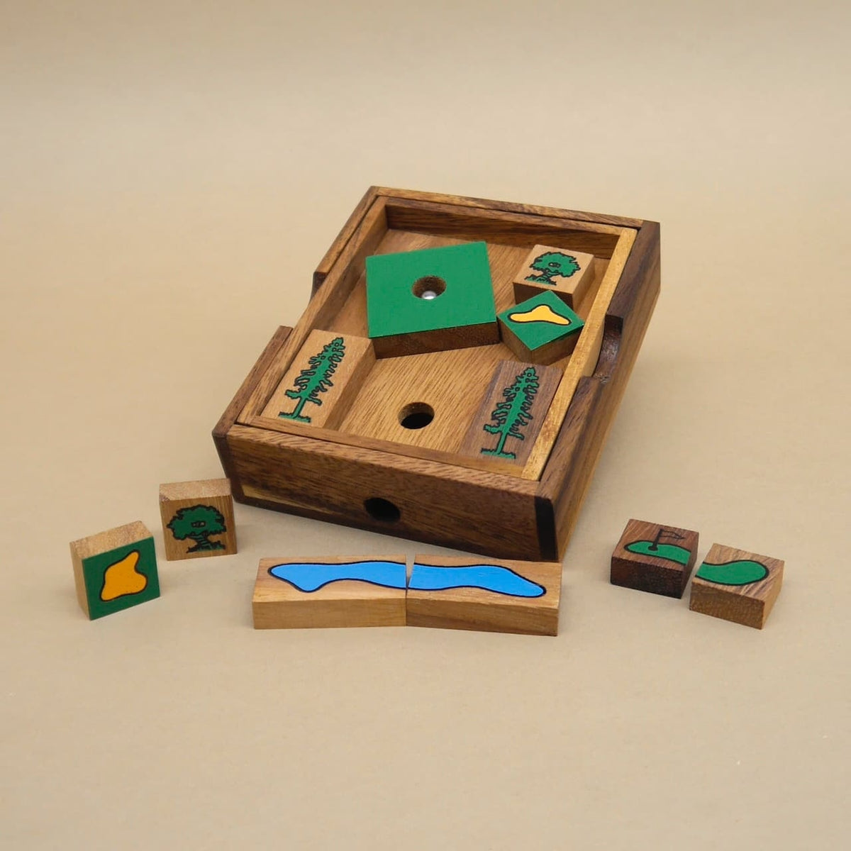 Teilweise gelöstes Knobelpuzzle in einer Holzschale; einige Golfmotive‑Steine liegen davor.