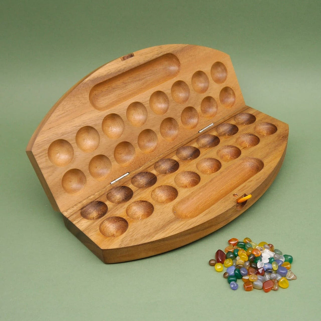 Edelsteinspiel als kompaktes Holzbrett, geöffnet; Mulden und bunte Glassteine liegen daneben