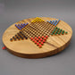 Ein rundes Halma-Brettspiel aus Holz in Sternform, vollständig aufgebaut mit farbigen Spielfiguren in Gelb, Blau, Grün, Rot und Schwarz. Die hochwertige Holzoberfläche und die präzise Anordnung der Löcher für die Spielfiguren unterstreichen das elegante De