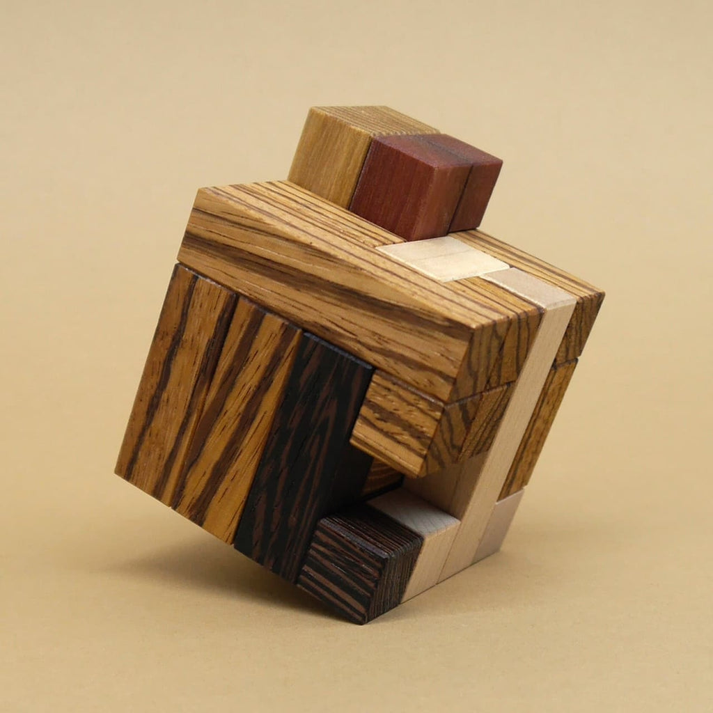 Zusammengesetztes 3D-Holzpuzzle in Würfelform, bestehend aus verschiedenen Holzarten mit unterschiedlichen Maserungen und Farben.