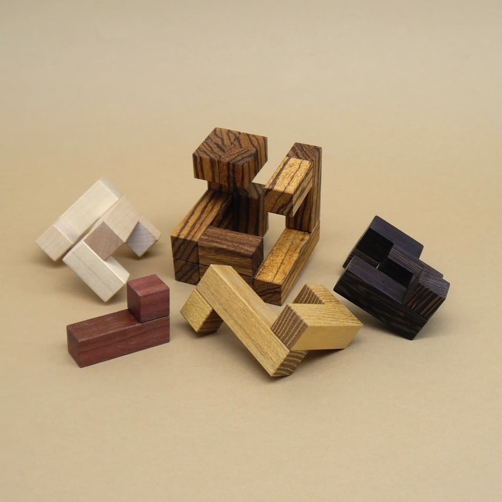 Einzelteile eines zerlegten Holzpuzzles in unterschiedlichen Farben und Formen, ausgebreitet auf einer hellen Unterlage.