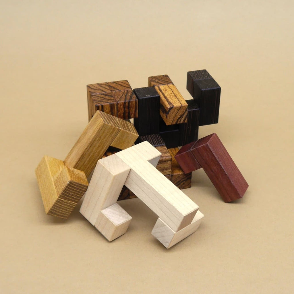 Durcheinandergelegte Bausteine eines Holzpuzzles in verschiedenen Holzarten, teilweise ineinandergesteckt.