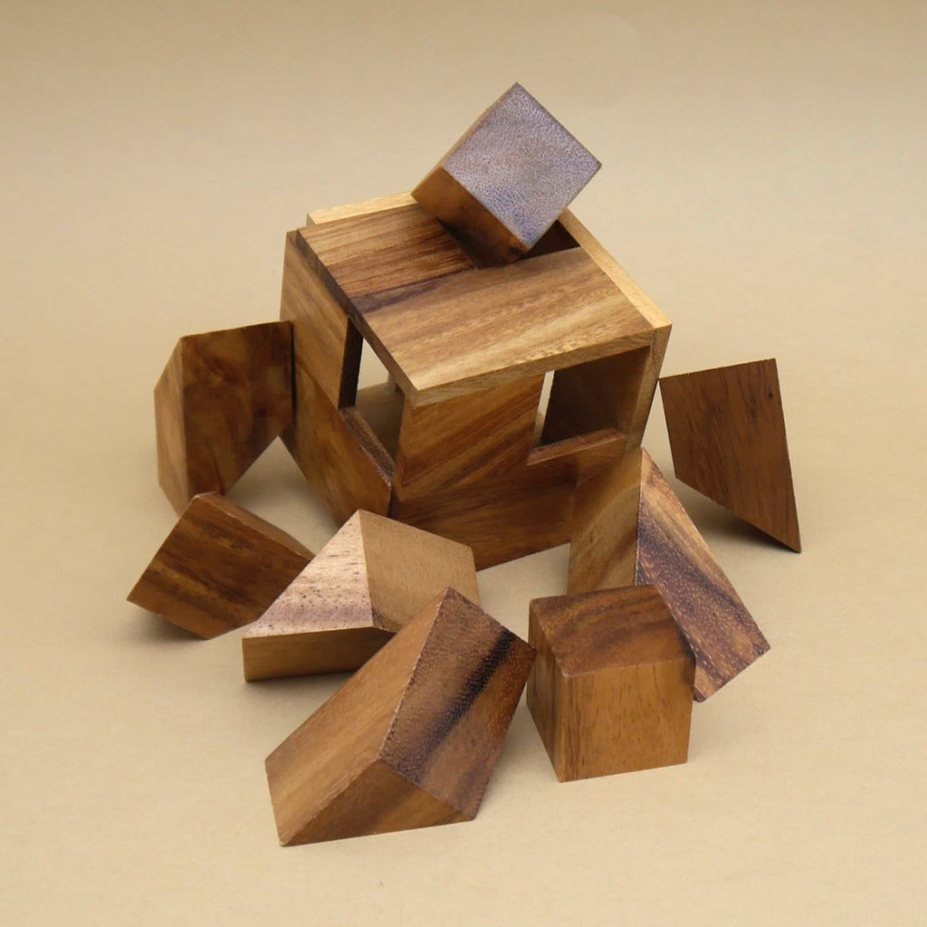 Zerlegtes Holz-3D-Puzzle „Hexahedroom“ mit offenem Würfelkörper und mehreren unterschiedlich geformten Teilen, die um den Würfel herumliegen.