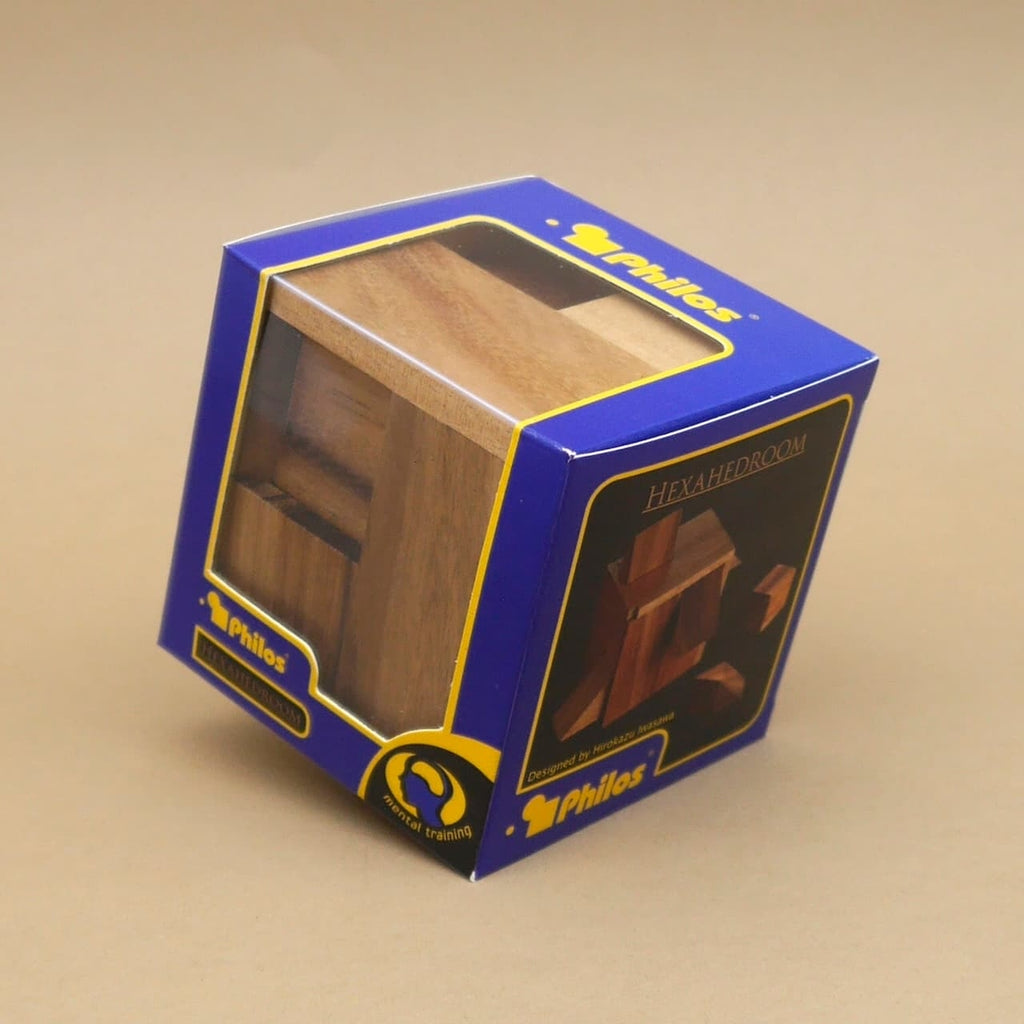 Blaue Verpackung der Knobelbox „Hexahedroom“ mit Sichtfenster, durch das der zusammengesetzte Holzwürfel zu sehen ist.