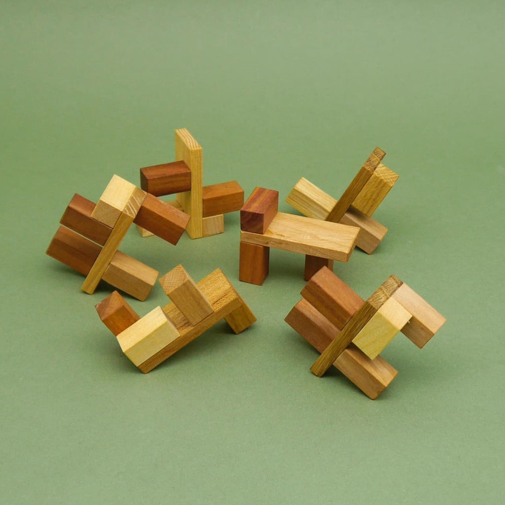 Zerlegte Teile des Holzpuzzles Hexator 3D-Puzzle in verschiedenen Holzfarben auf grünem Hintergrund.