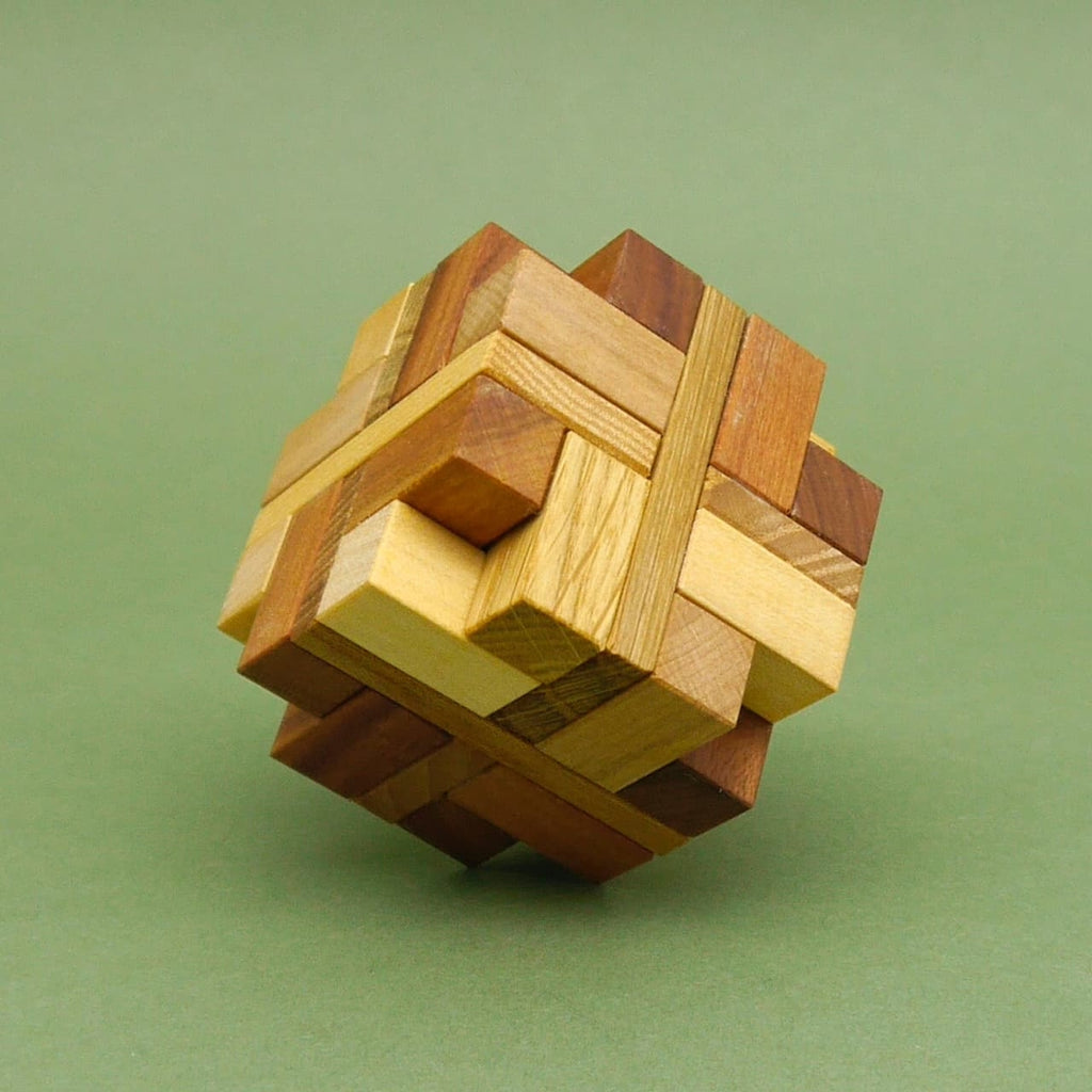 Komplett zusammengesetztes Hexator Denkspiel als komplexer Holzwürfel auf grünem Hintergrund.
