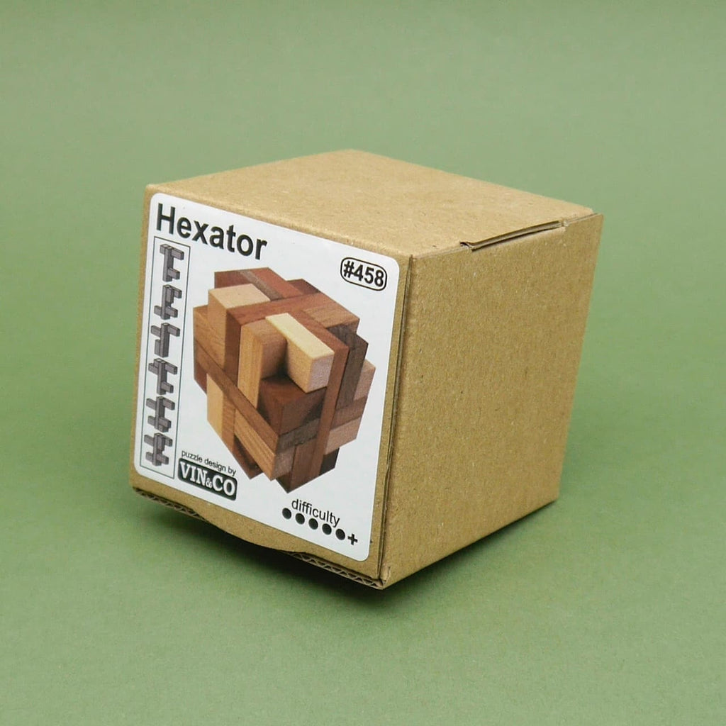 Nahaufnahme der Kartonverpackung des Hexator Knobelspiel Holzwürfel mit Abbildung des Holzpuzzles auf grünem Hintergrund.