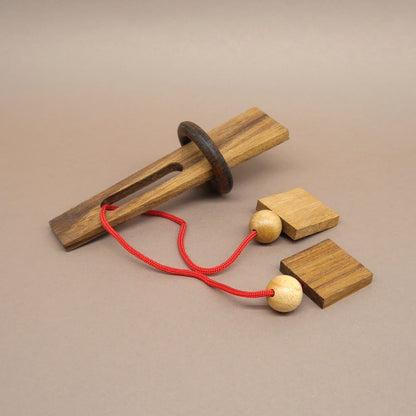 Anspruchsvolles Holzpuzzle mit Schnur, Kugeln und Holzring – ein Denkspiel für Knobelfreunde.