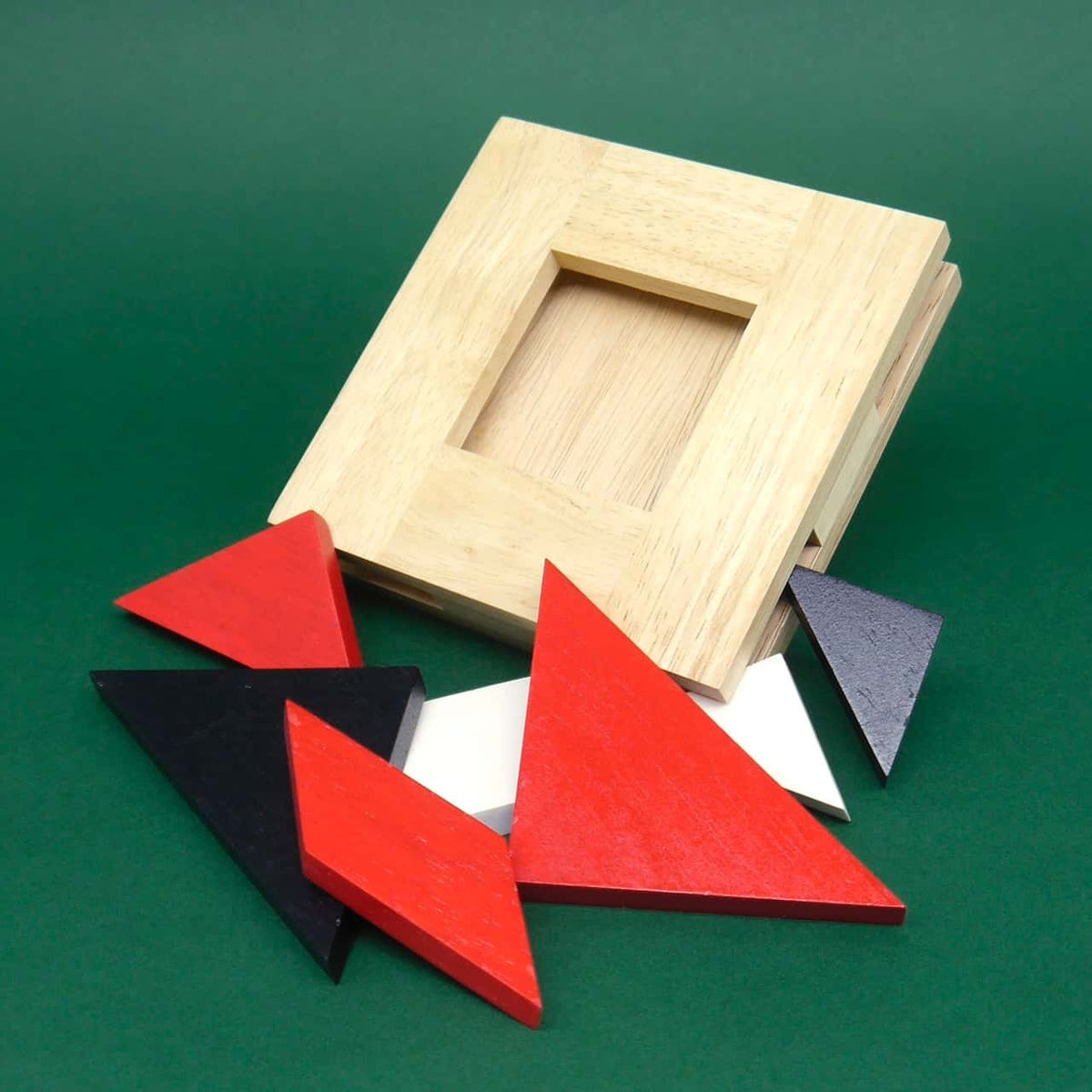  Offener Holzrahmen mit verstreuten roten, schwarzen und weißen Tangram-Teilen – anspruchsvolles Geduldsspiel in Einzelteilen.