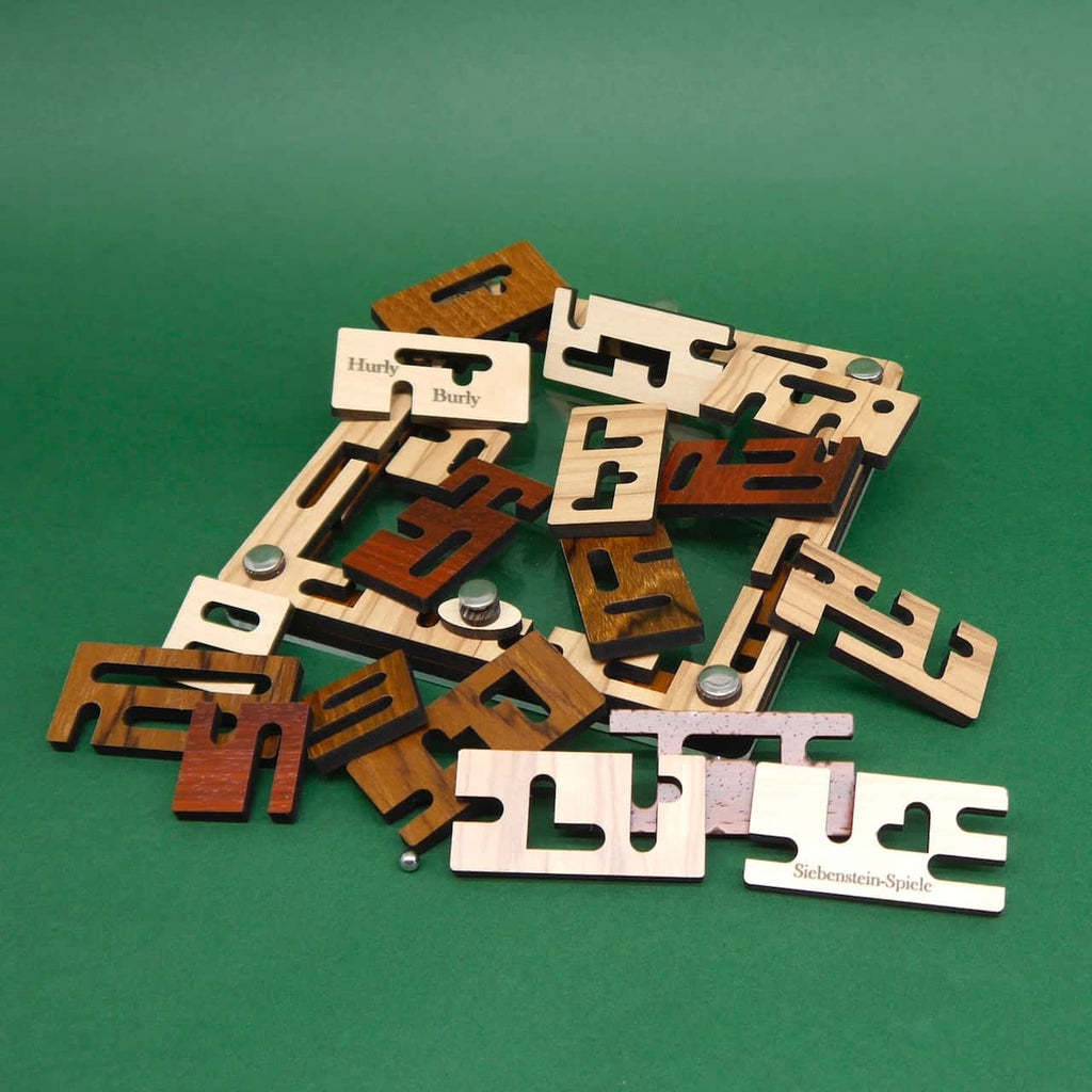Ein Haufen gemischter „Hurly Burly“-Holzplättchen, Metallschrauben und zwei Stahlkugeln auf grünem Tisch – das Puzzle ist vollständig zerlegt.