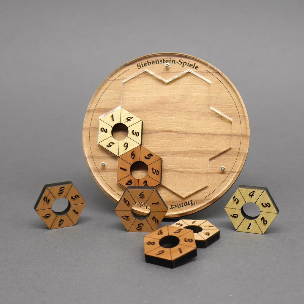 Ein teilweise bestücktes Knobelspiel: nummerierte, sechseckige Holzringe werden in eine runde Grundplatte eingesetzt.
