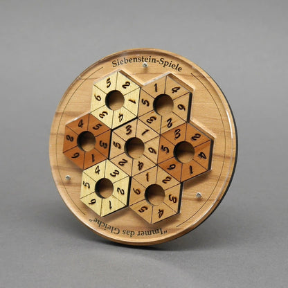 Das komplett ausgefüllte Zahlenpuzzle zeigt eine wabenförmige Fläche aus hellen und dunklen Sechseckringen mit Ziffern und zentralen Löchern.