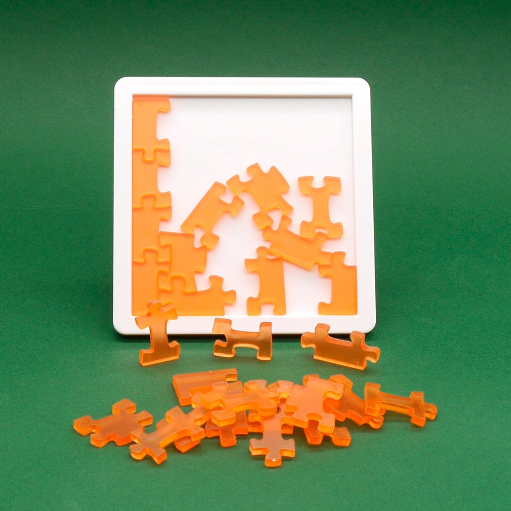 Teilweise gelöstes Logikspiel mit orangefarbenen Puzzleteilen auf weißem Rahmen vor grünem Hintergrund.