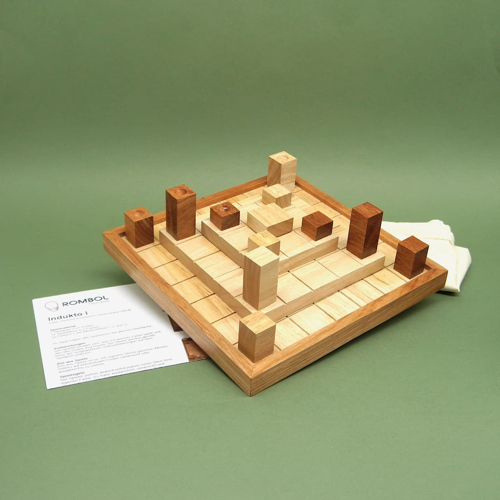 Indukto Brettspiel komplett aufgebaut mit Holzklötzen, Spielbrett und Anleitung; Baumwollbeutel daneben.