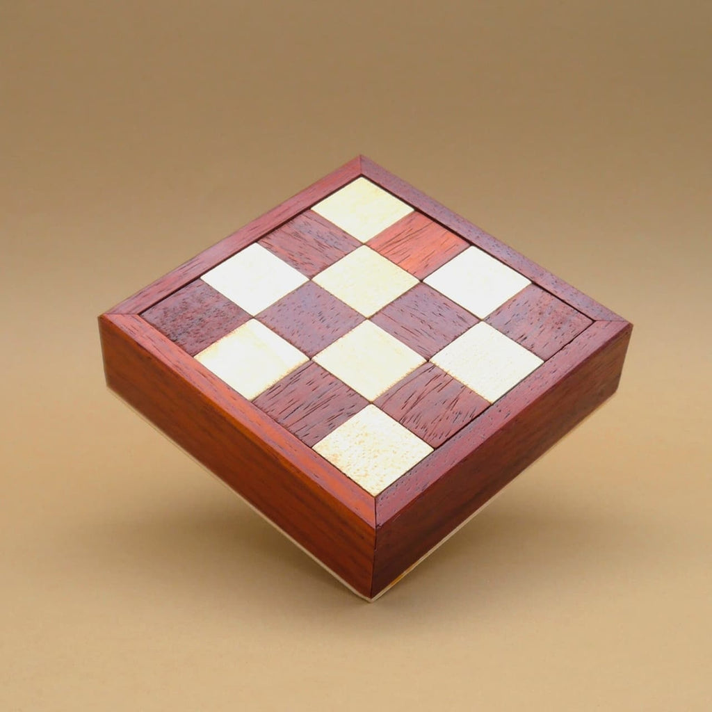 Quadratische Knobelbox als abgeschlossenes Packpuzzle mit sauber eingelegten Holzsteinen.