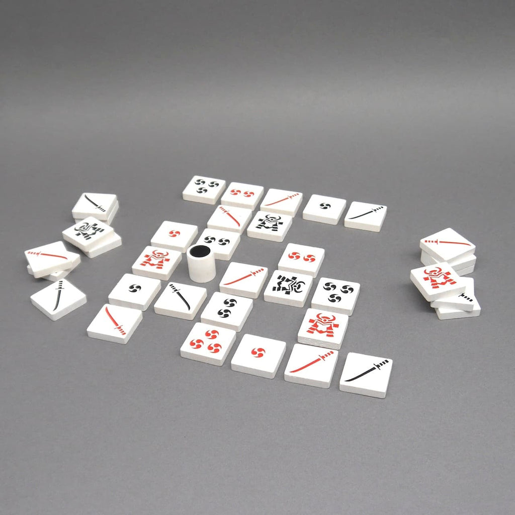 Spielsteine des Strategiespiels Kaito sind auf grauem Untergrund ausgelegt – ein Denkspiel für zwei Spieler mit asiatischem Design.