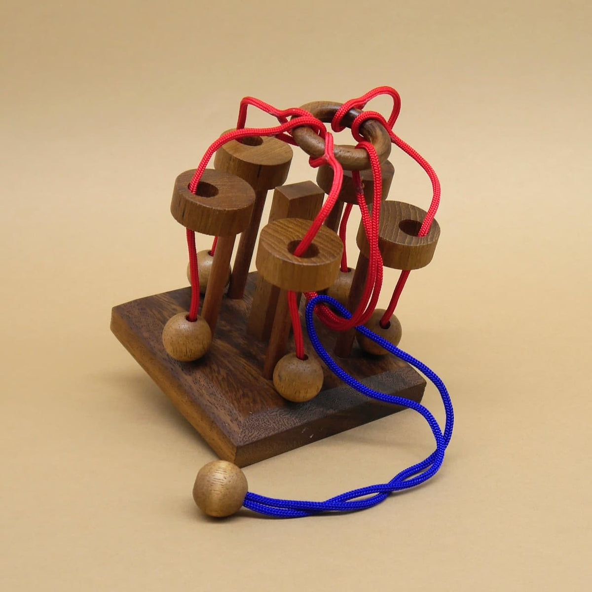 Seilpuzzle aus Holz mit roten und blauen Schnüren – ein Denkspiel zum Knobeln.