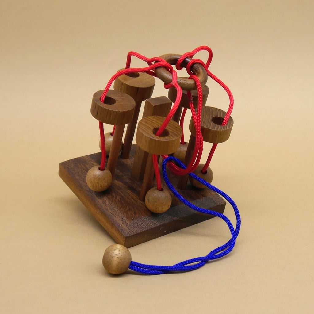 Seilpuzzle aus Holz mit roten und blauen Schnüren – ein Denkspiel zum Knobeln.