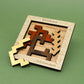 Quadratisches Holzpuzzle „Kleinkunst” von Siebenstein-Spiele mit unterschiedlich geformten und farbigen Holzteilen, teils aus dem Rahmen genommen.