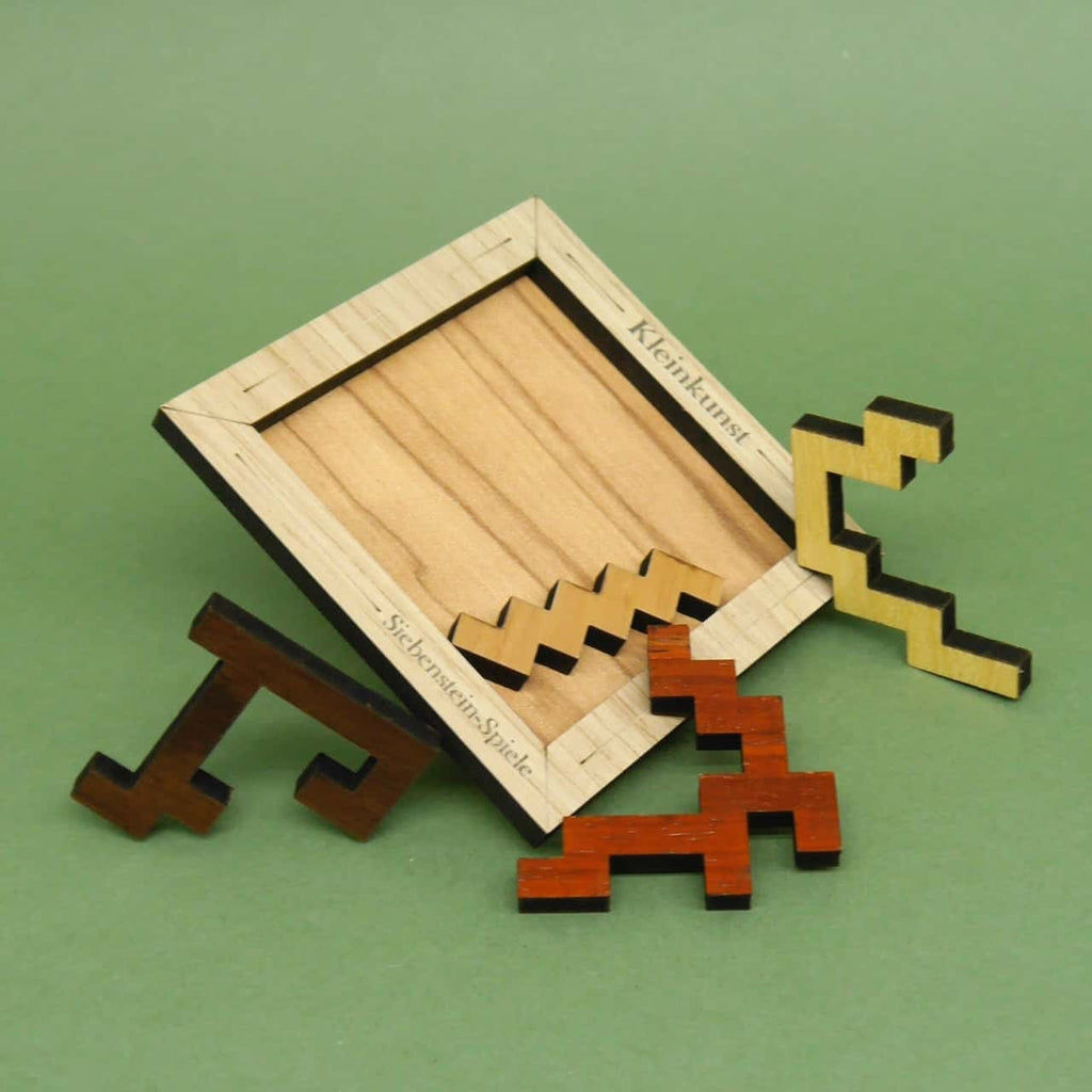 Leerer Holzrahmen des Puzzles „Kleinkunst” von Siebenstein-Spiele mit mehreren Zickzack-förmigen Holzteilen in verschiedenen Tönen davor.