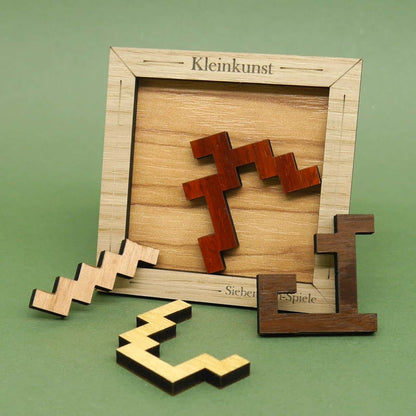 Holzpuzzle „Kleinkunst” von Siebenstein-Spiele in Nahaufnahme, bei dem mehrere farbige, winkelförmige Teile teilweise im Rahmen und teilweise davor liegen.