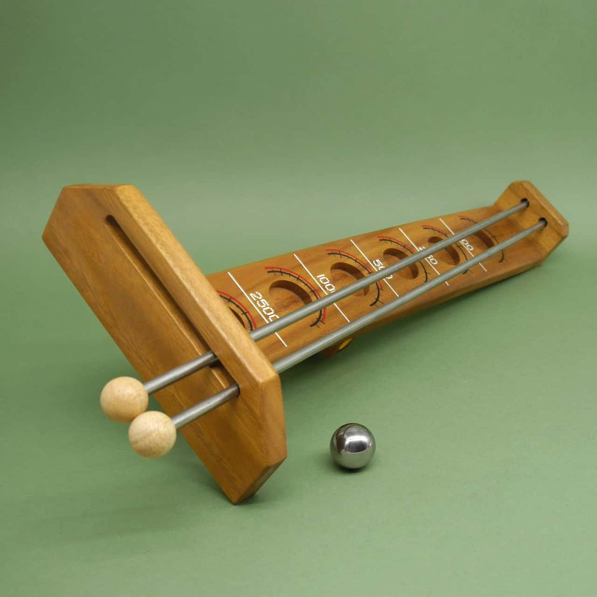 Traditionelles game of skill: hölzerne Bahn mit Punkte-Skala liegt flach, eine Stahlkugel wartet startbereit davor.