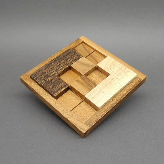 Das denkspiel aus Holz zeigt bereits gelöste Muster aus verschiedenfarbigen Steinen, die bündig in das Raster passen.