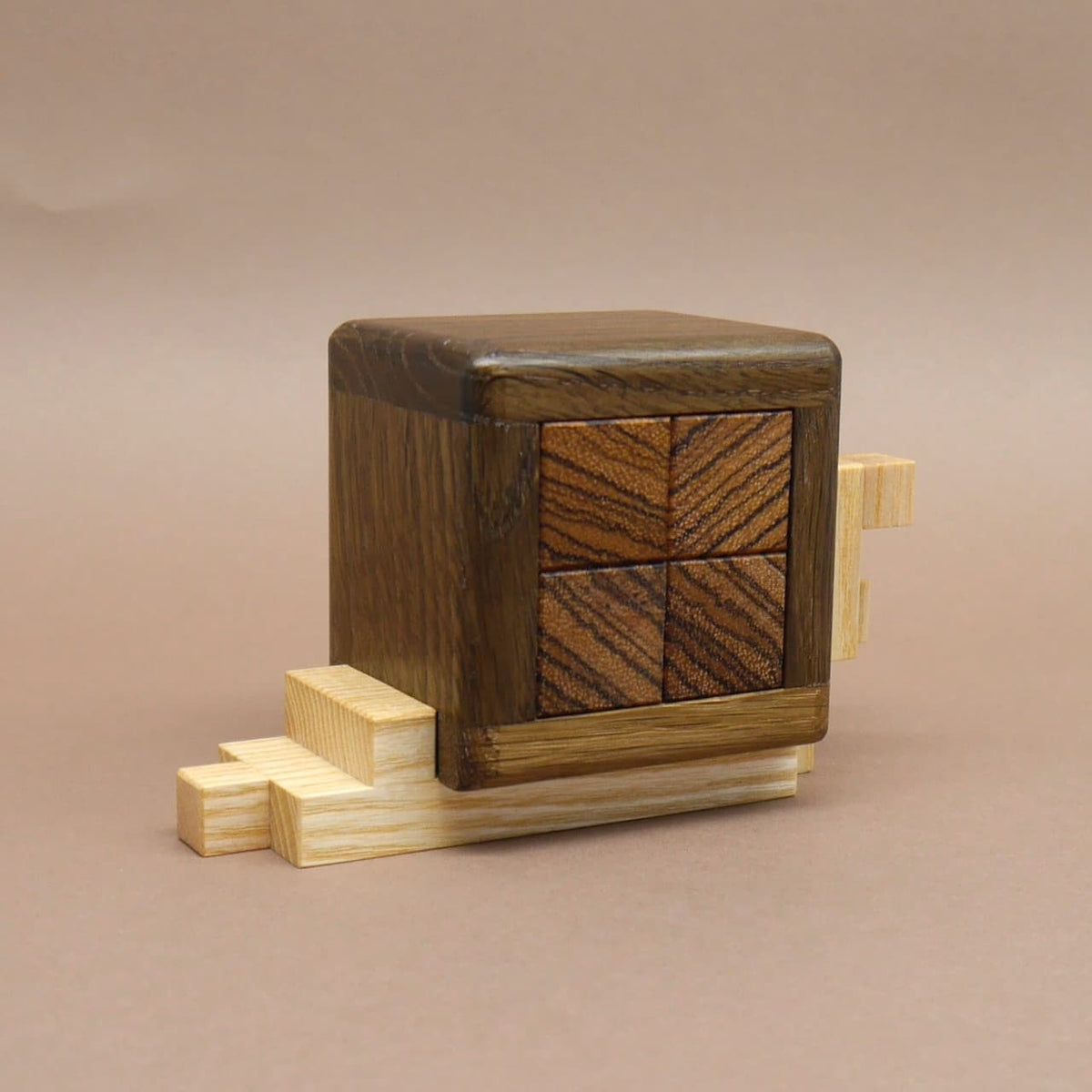 Vierteiliges Schnecken‑Interlocking‑Objekt aus Holz, dessen Stufen das Knobelspiel schon andeuten.
