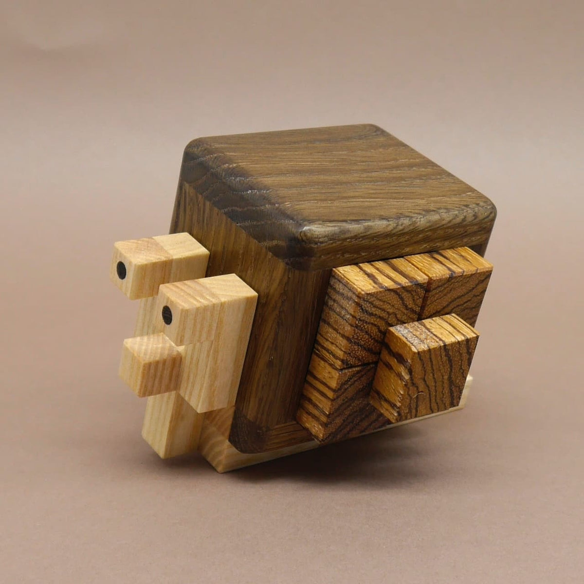 Charmantes Schnecken‑Braingame aus kontrastierendem Holz, schräg aufgestellt als dekoratives Objekt.