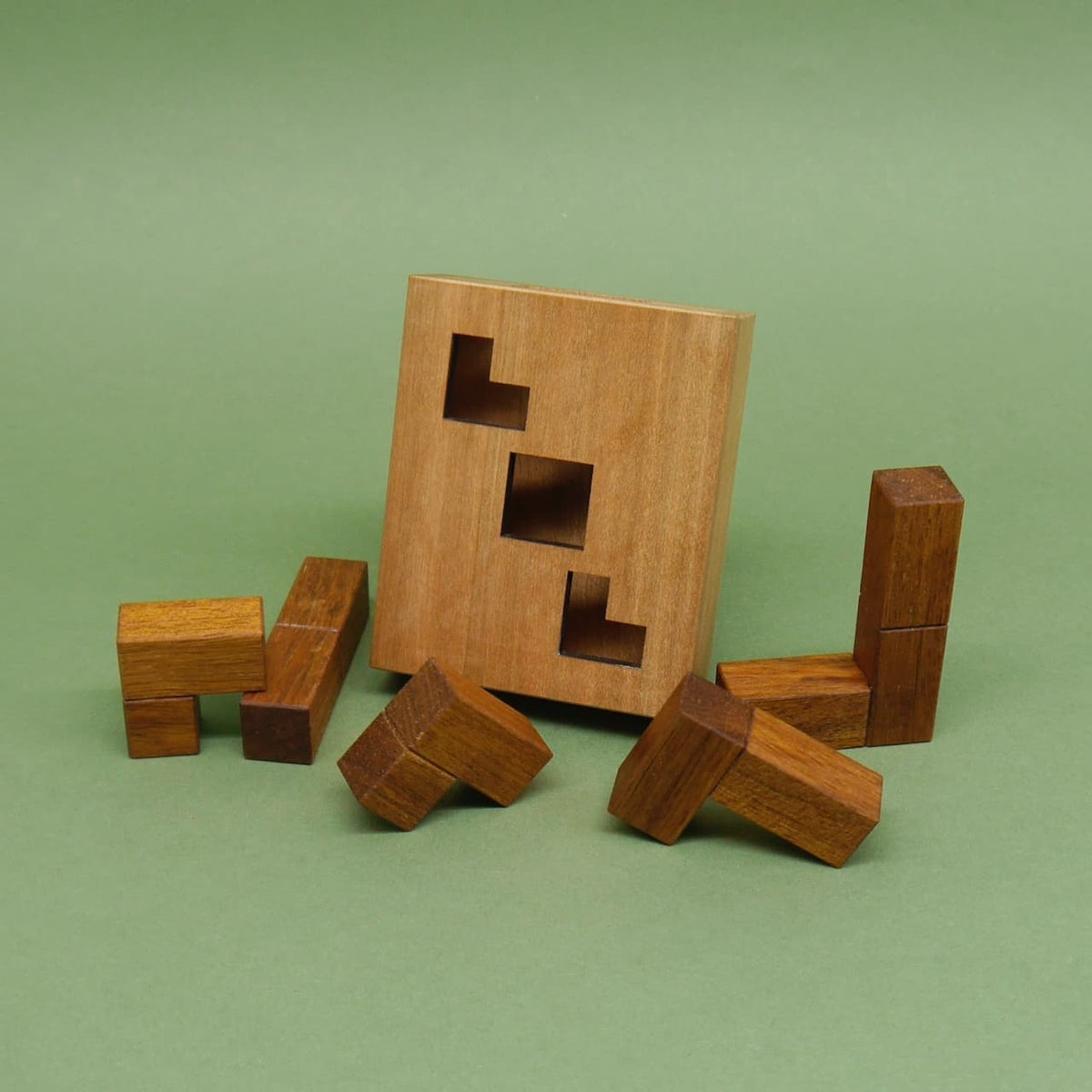 Logikpuzzle: einzelne Formsteine lehnen an einer Holzplatte mit drei quadratischen Öffnungen.