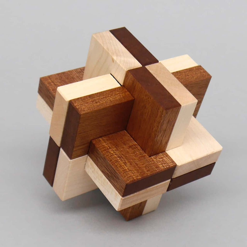 Geduldsspiel aus hellen und dunklen Holzquadern, die zu einem sternförmigen 3-D-Knoten lückenlos ineinandergreifen.