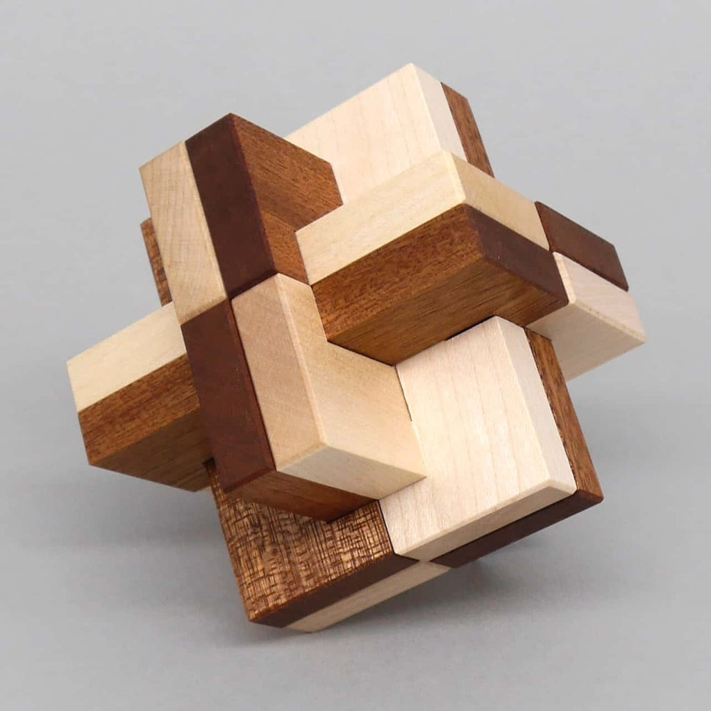Denkspiel aus unterschiedlich gemaserten Holzteilen, als komplexes Interlocking-Gebilde würfelförmig verschachtelt.
