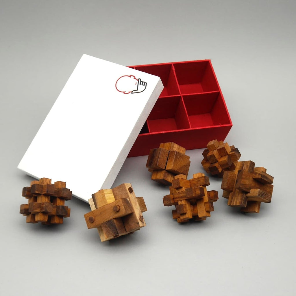 Geöffnete rote Box mit Fächern und sechs hölzernen Geduldsspiele für Denksport und Konzentration.