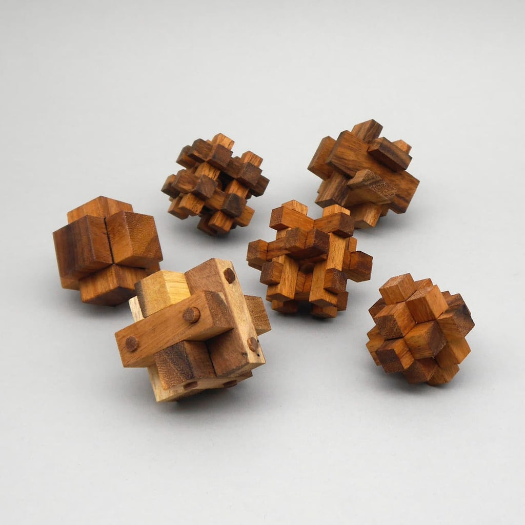 Sechs handgefertigte Knobelspiele aus Holz als Geschenkset; verschiedene 3D-Puzzles auf neutralem Hintergrund.