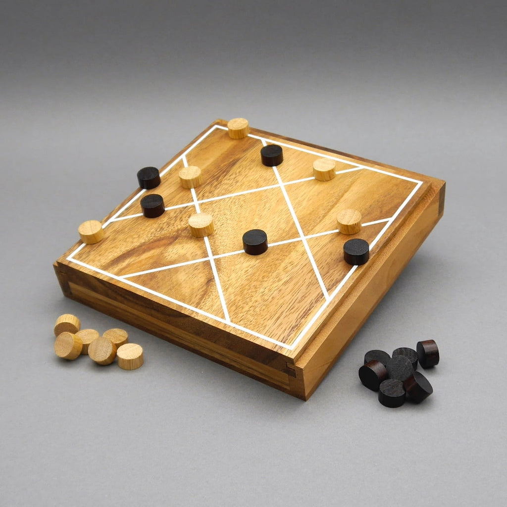 Taktikspiel „Lücke mit Tücke“: quadratisches Holzbrett mit weißen Linien, helle und dunkle runde Steine in Spielsituation auf dem Feld.