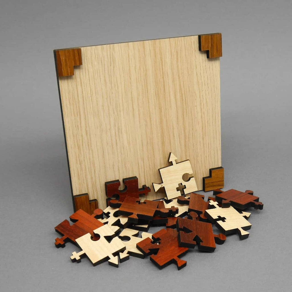 Leeres quadratisches Holzbrett; davor ein Haufen rotbrauner und heller Puzzleteile mit verschiedenen Symbol-Verbindern, bereit zum Einsetzen.